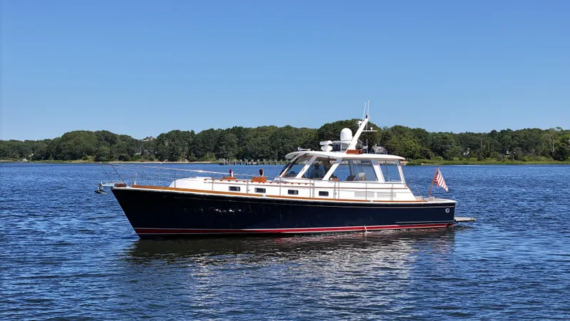 Slide: The Image of 2002 Grand Banks 49 Eastbay HX yacht on calm water, clear sky, lush shoreline. - 6