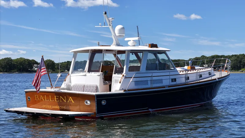 Slide: The Image of 2002 Grand Banks 49 Eastbay HX yacht on water, clear sky, American flag displayed. - 8