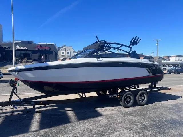 Slide: The Image of 2025 Cobalt R6 Surf boat on trailer, parked outdoors under clear blue sky. - 3