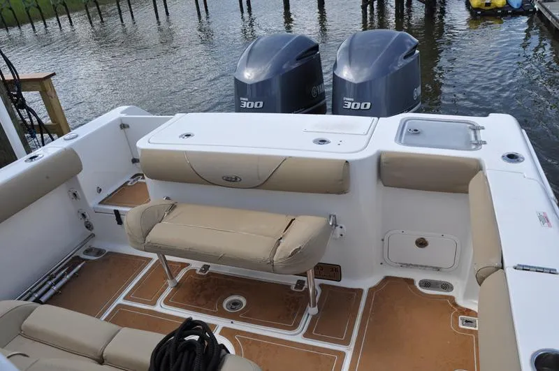 Slide: The Image of 2015 Sea Hunt Gamefish 30 boat interior with dual Yamaha 300 engines, docked by the water. - 10