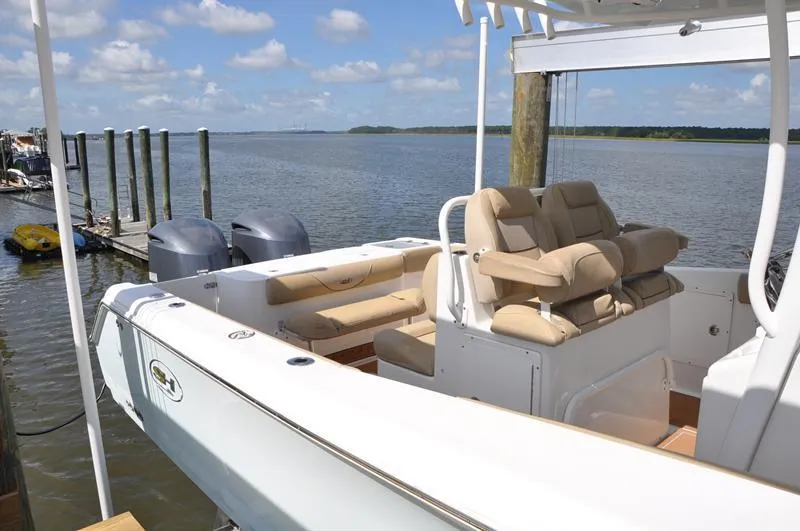 Slide: The Image of 2015 Sea Hunt Gamefish 30 boat docked, featuring comfortable seating and dual outboard motors. - 2