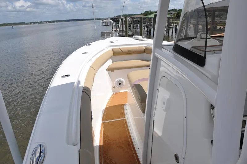 Slide: The Image of 2015 Sea Hunt Gamefish 30 boat interior with cushioned seating, docked by calm waters. - 22