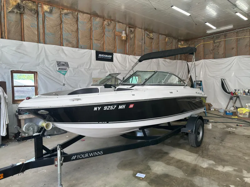 Slide: The Image of 2011 Four Winns H180 boat on trailer in a garage setting. - 12