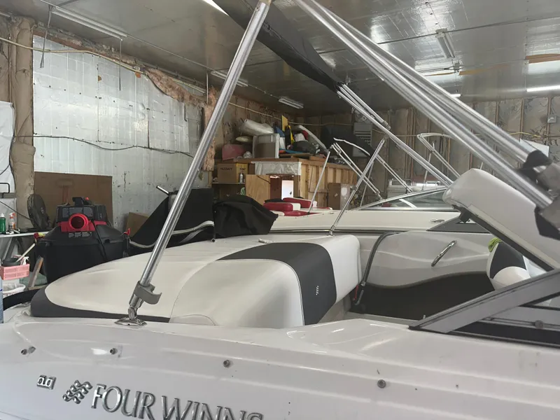 Slide: The Image of 2011 Four Winns H180 boat in a garage, showcasing interior seating and structure. - 13