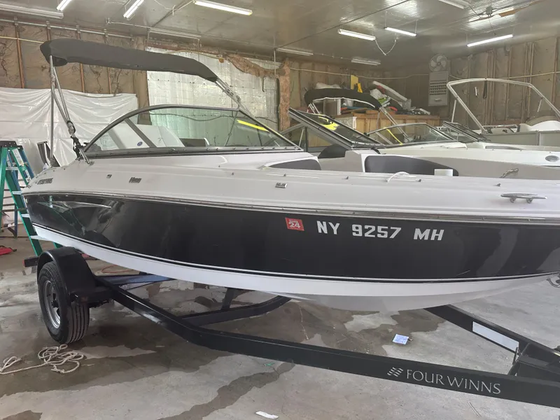 Slide: The Image of 2011 Four Winns H180 boat in a garage, black and white exterior, on a trailer. - 14