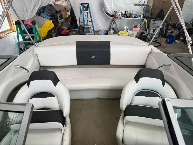 Slide: The Image of 2011 Four Winns H180 boat interior with white and black seating in a garage setting. - 6