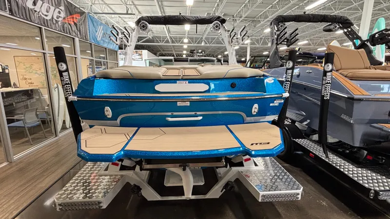 Slide: The Image of 2025 MB B52 23 Classic boat in showroom, blue exterior, wakeboard racks, luxury seating. - 10