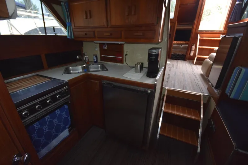 Slide: The Image of 1985 Marinette 39 Double Cabin kitchen with stove, sink, and compact fridge. - 49