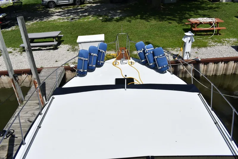 Slide: The Image of 1985 Marinette 39 Double Cabin docked, featuring spacious deck with blue chairs and picnic area nearby. - 22