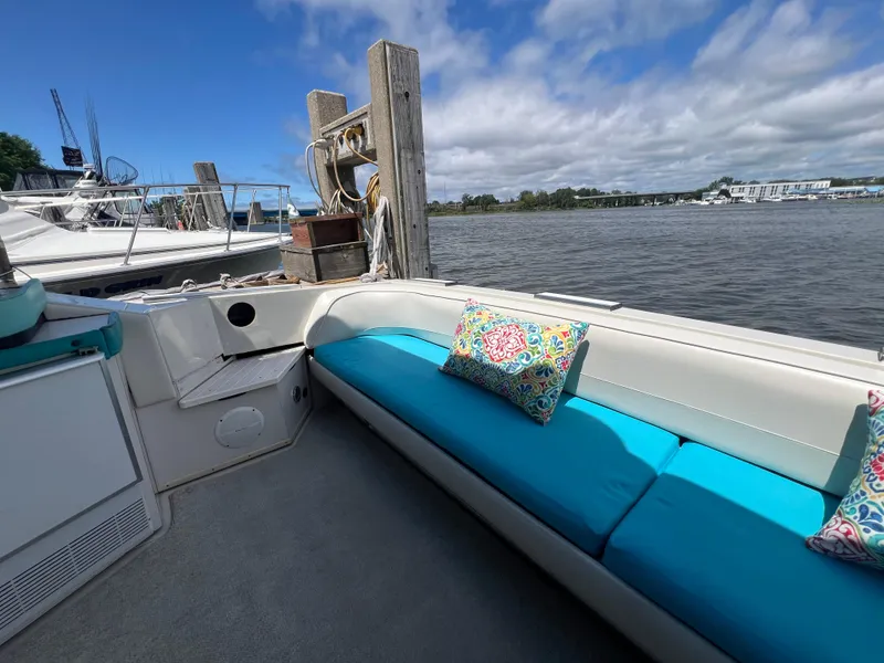Slide: The Image of 1988 Wellcraft 3400 Grand Sport boat interior with blue seating and colorful pillows by the water. - 10