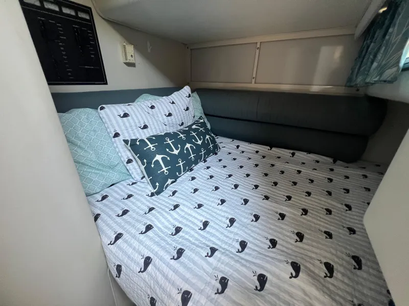 Slide: The Image of Cozy cabin bed in 1988 Wellcraft 3400 Grand Sport with nautical-themed bedding. - 23