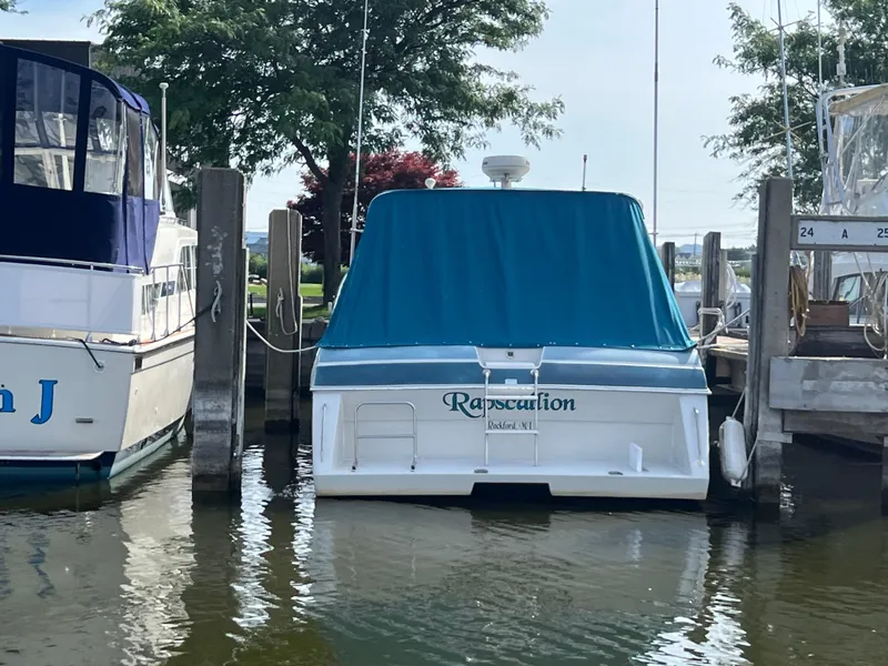 Slide: The Image of 1988 Wellcraft 3400 Grand Sport boat docked with blue cover, surrounded by other boats. - 3