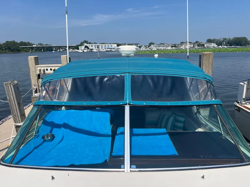 Slide: The Image of 1988 Wellcraft 3400 Grand Sport boat docked by a scenic waterfront. - 5