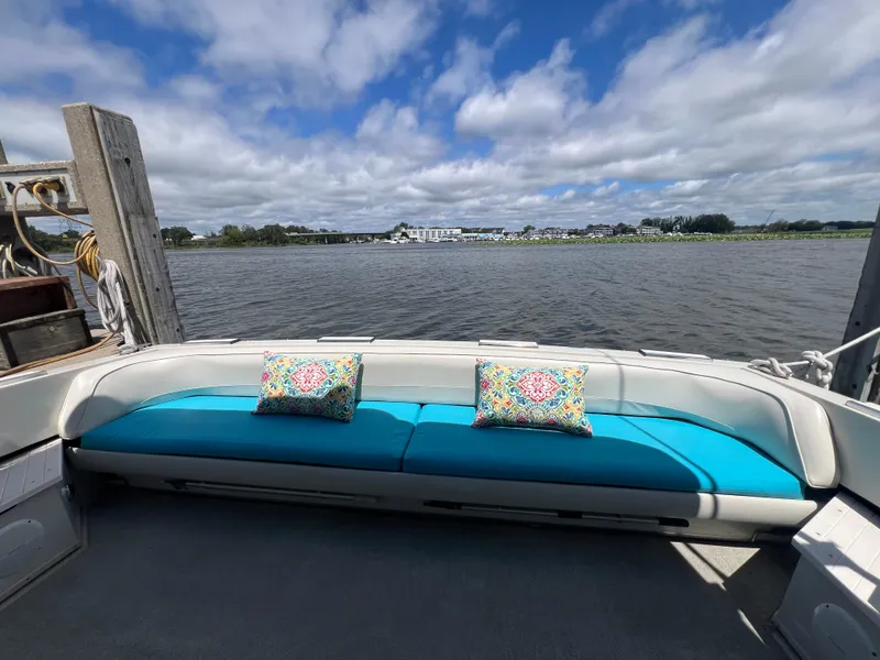 Slide: The Image of 1988 Wellcraft 3400 Grand Sport boat with blue seating and decorative pillows, docked by a scenic river. - 8
