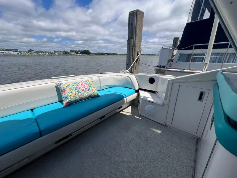 Slide: The Image of 1988 Wellcraft 3400 Grand Sport boat interior with blue seating and colorful pillow, docked by the water. - 9