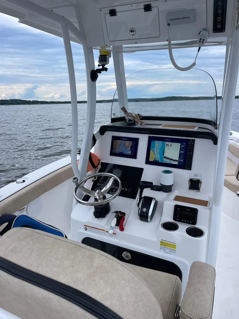 Slide: The Image of 2022 Sea Pro 239 Center Console boat dashboard with navigation screens on a calm lake. - 9
