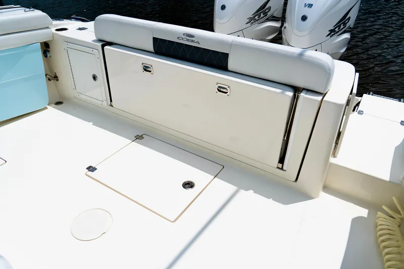 Slide: The Image of 2024 Cobia 350 boat deck with storage and twin outboard engines. - 12