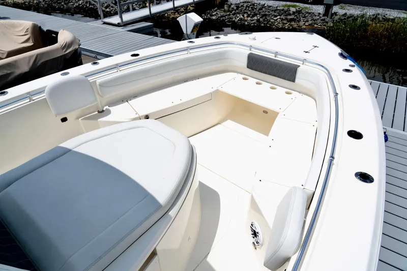 Slide: The Image of 2024 Cobia 350 boat interior with white seating and storage compartments at a dock. - 13
