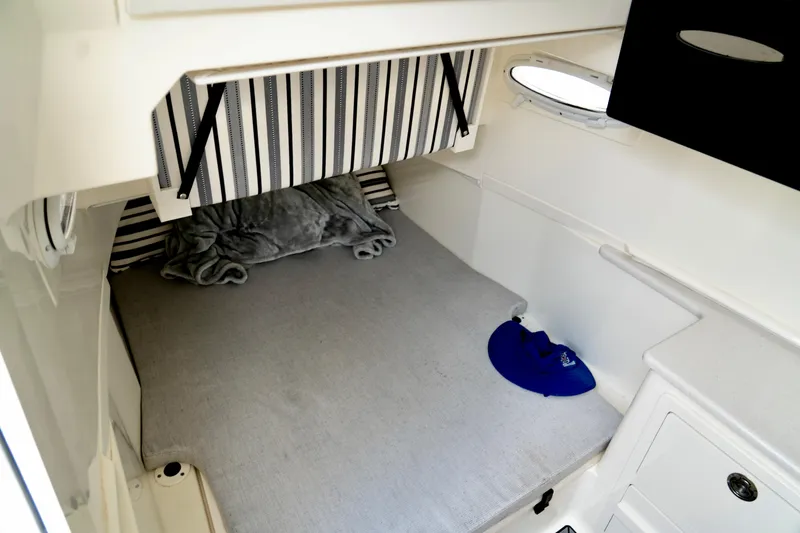 Slide: The Image of 2024 Cobia 350 cabin interior with bed, striped curtain, and porthole window. - 16