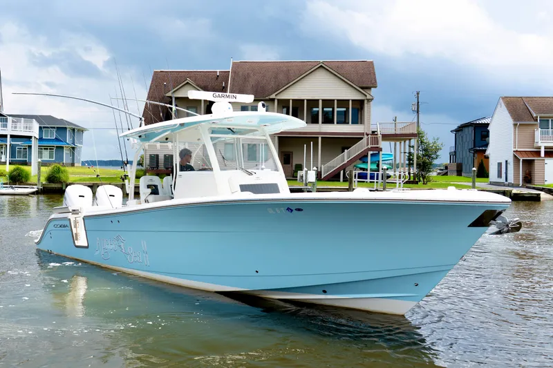 Slide: The Image of 2024 Cobia 350 boat on water near waterfront homes, under cloudy sky. - 2