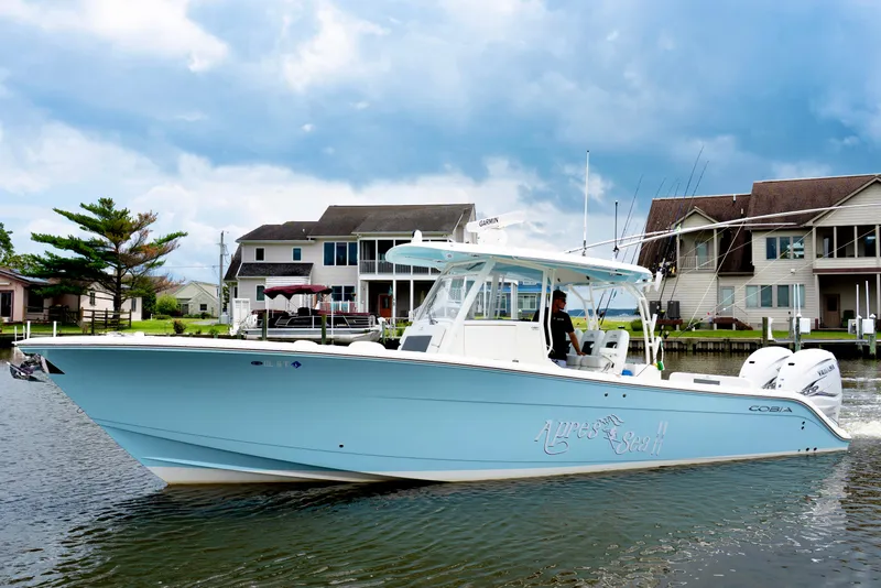 Slide: The Image of 2024 Cobia 350 boat on water near residential homes, under a cloudy sky. - 5