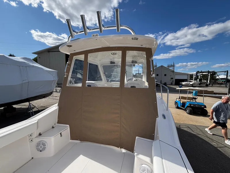 Slide: The Image of 2026 NorthCoast 235 HT boat with covered cabin, docked under a clear blue sky. - 7