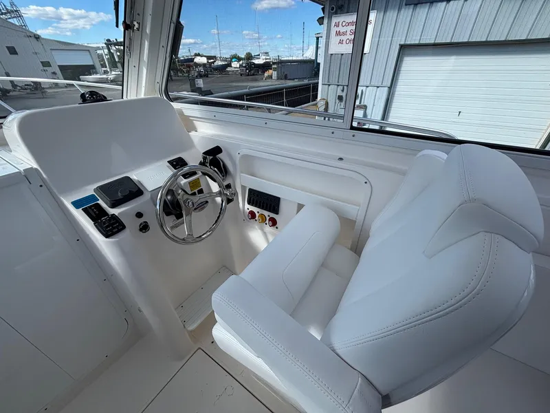 Slide: The Image of Interior of 2026 NorthCoast 235 HT boat, featuring helm and white captain's chair. - 8