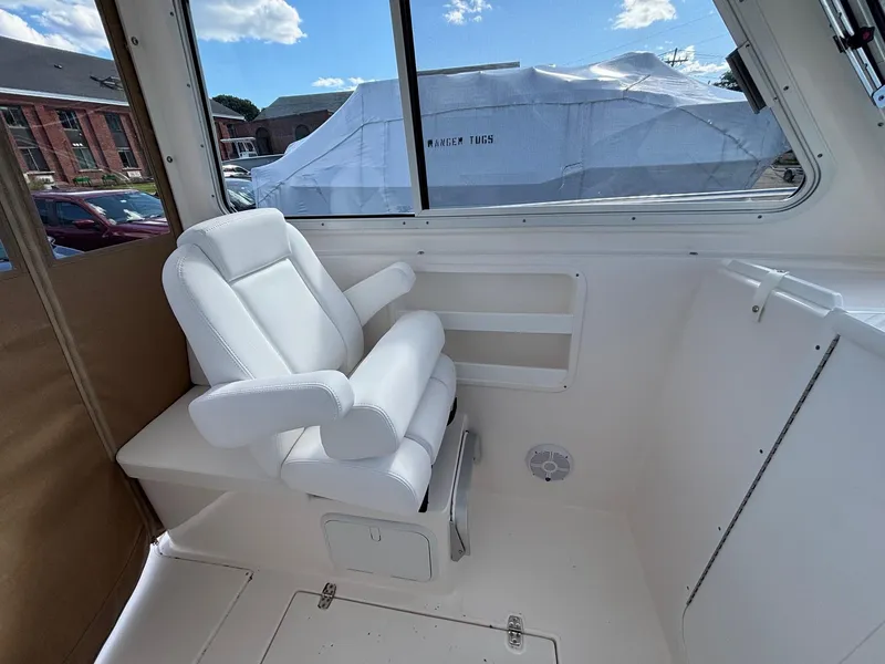 Slide: The Image of White captain's chair inside 2026 NorthCoast 235 HT boat, with window view. - 9