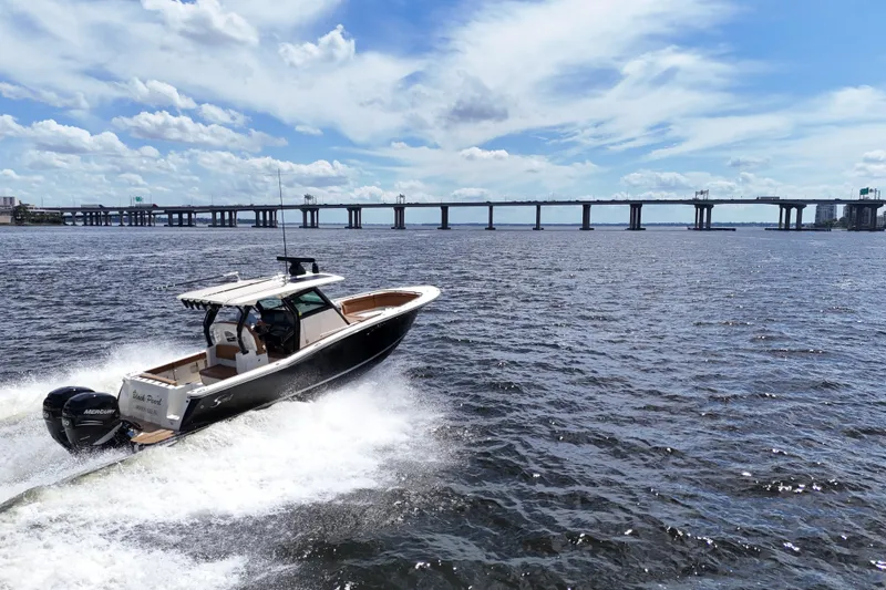 Slide: The Image of 2021 Scout 330 LXF boat cruising on open water under a blue sky. - 100