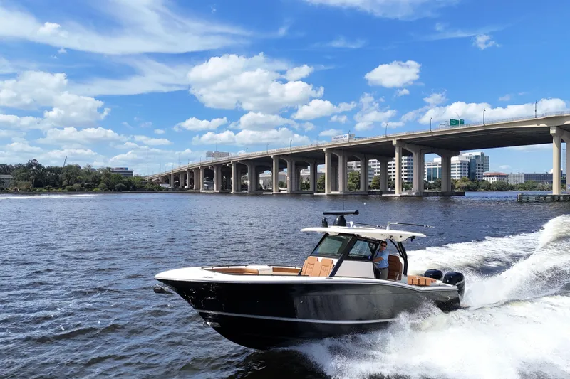 Slide: The Image of 2021 Scout 330 LXF boat cruising on a river under a clear blue sky. - 102