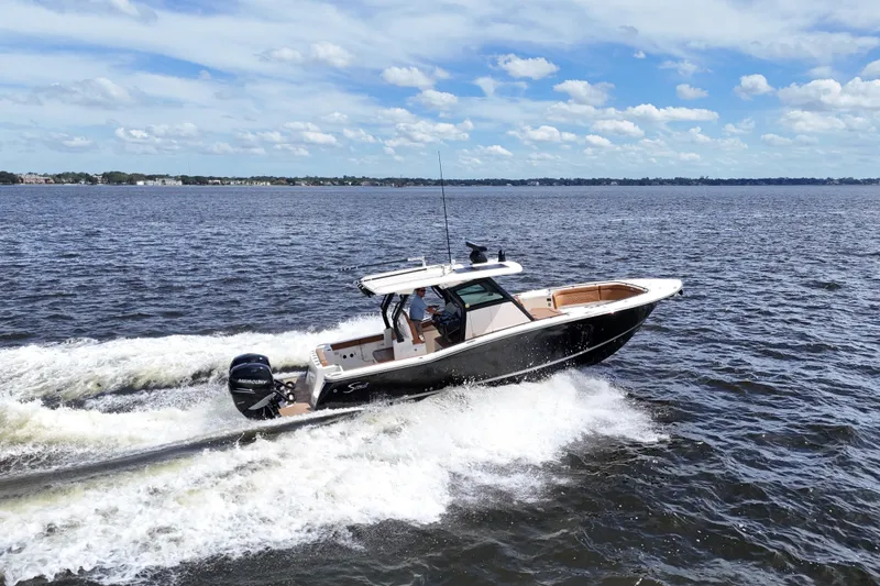 Slide: The Image of 2021 Scout 330 LXF boat cruising on open water under a partly cloudy sky. - 103