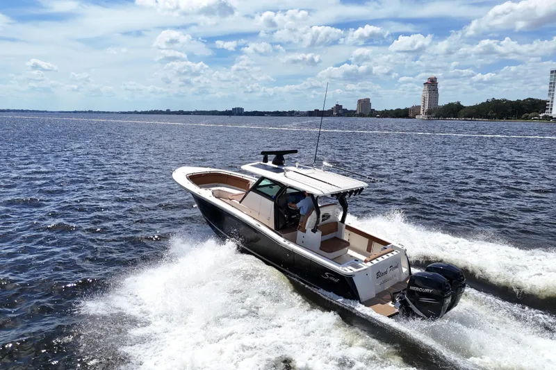 Slide: The Image of 2021 Scout 330 LXF boat cruising on open water under a partly cloudy sky. - 104