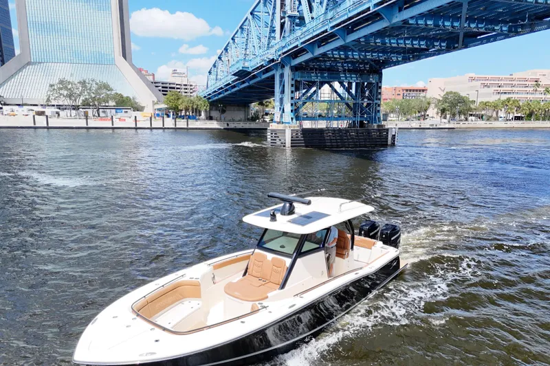 Slide: The Image of 2021 Scout 330 LXF boat cruising under a blue bridge in a cityscape setting. - 17