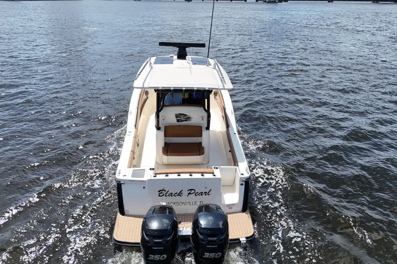 Slide: The Image of 2021 Scout 330 LXF boat cruising on water, rear view with twin engines. - 21