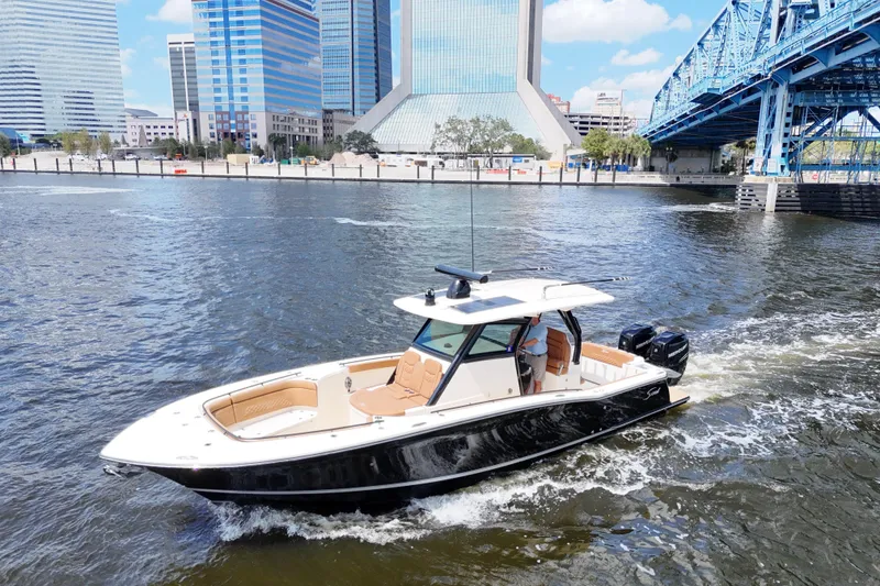 Slide: The Image of 2021 Scout 330 LXF boat cruising near cityscape and bridge on a sunny day. - 23