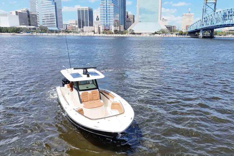 Slide: The Image of 2021 Scout 330 LXF boat cruising near city skyline and bridge. - 28