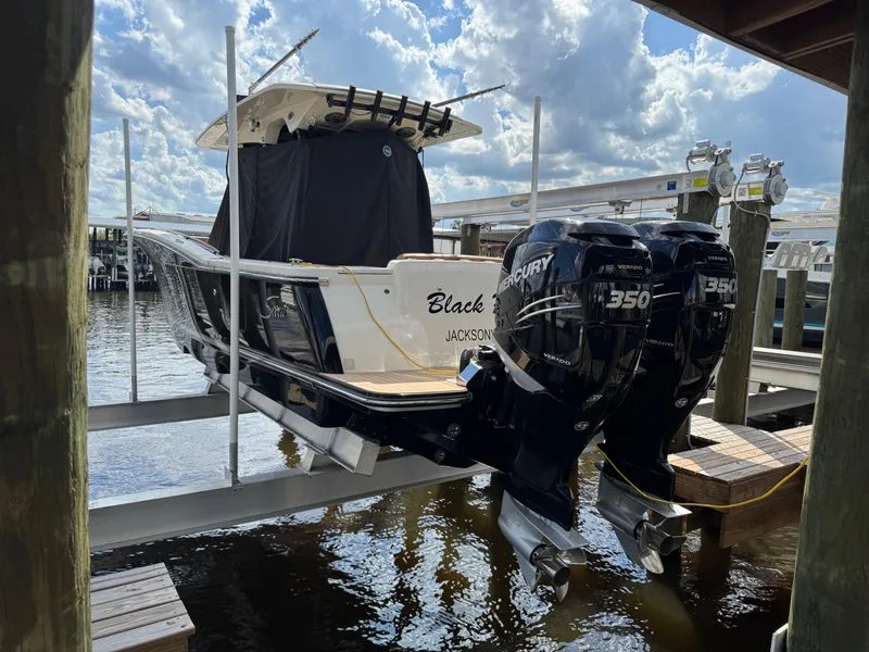 Slide: The Image of 2021 Scout 330 LXF boat with twin Mercury 350 engines docked at marina. - 31