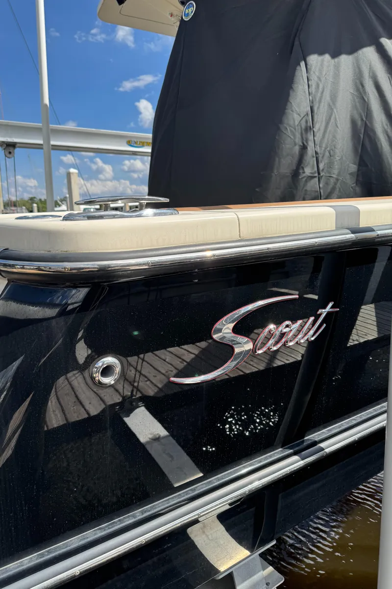 Slide: The Image of 2021 Scout 330 LXF boat with sleek black exterior and logo, docked under a sunny sky. - 36