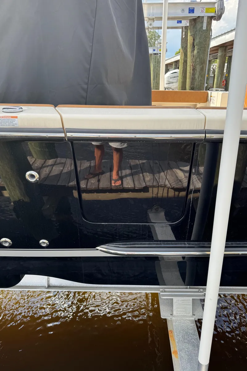Slide: The Image of 2021 Scout 330 LXF boat docked, reflecting surroundings on glossy black hull. - 40