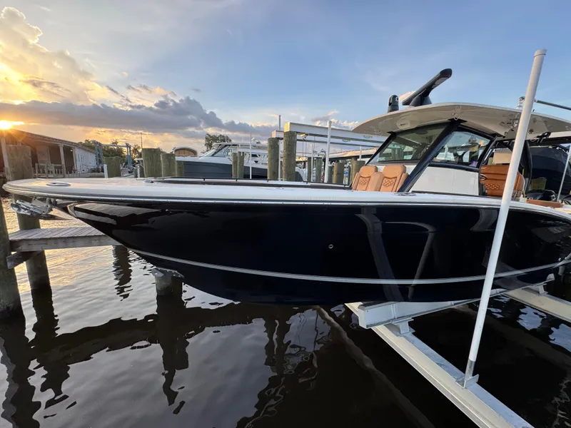 Slide: The Image of 2021 Scout 330 LXF boat docked at sunset, reflecting on calm water. - 41