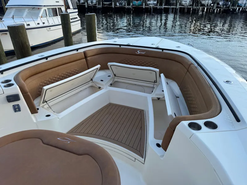 Slide: The Image of 2021 Scout 330 LXF boat interior with open storage compartments, docked by the water. - 50