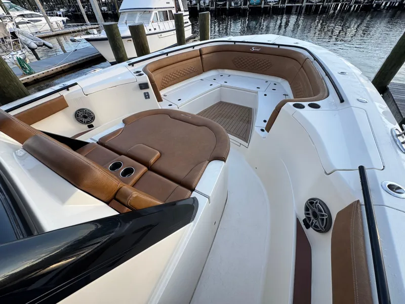 Slide: The Image of 2021 Scout 330 LXF boat interior with brown leather seating and cup holders. - 52