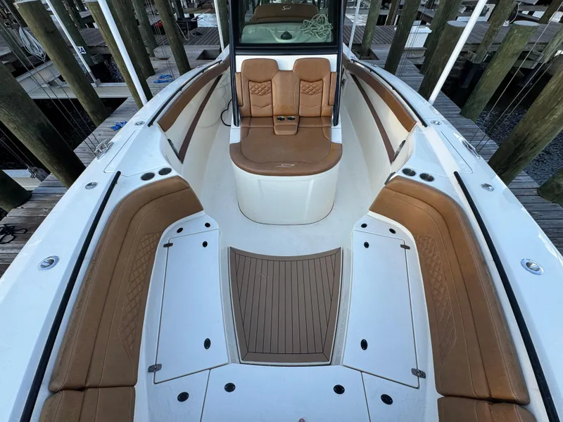 Slide: The Image of 2021 Scout 330 LXF boat interior with tan seating and white deck, docked at marina. - 57