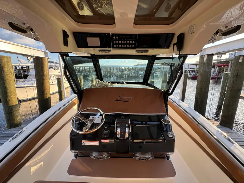 Slide: The Image of 2021 Scout 330 LXF boat helm with steering wheel and controls at marina dock. - 61