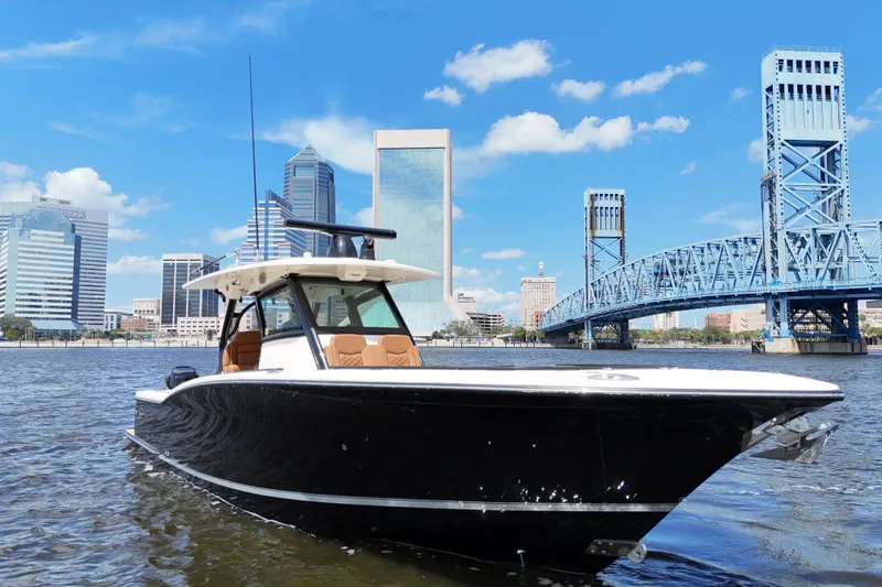 Slide: The Image of 2021 Scout 330 LXF boat on water with city skyline and bridge background. - 7