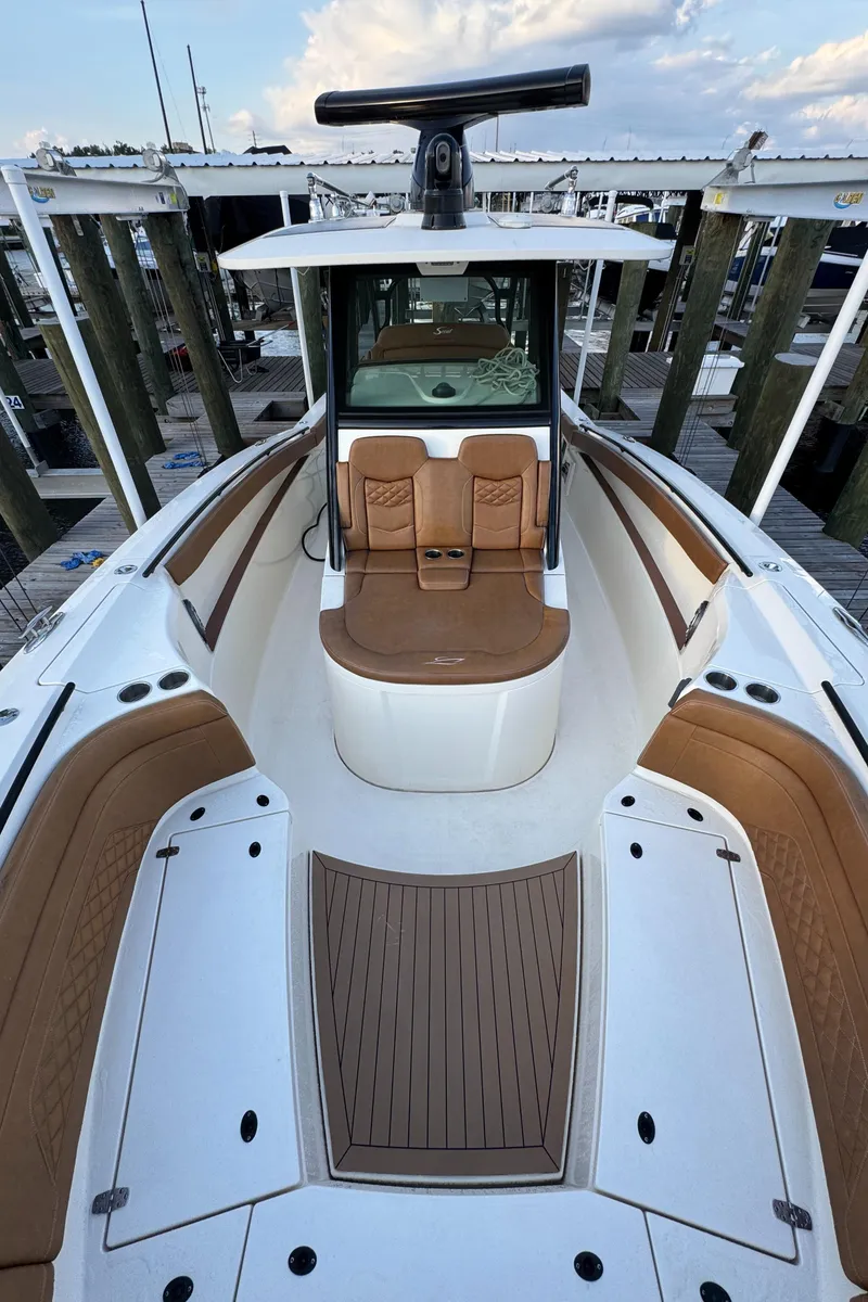 Slide: The Image of 2021 Scout 330 LXF boat with brown seating and white deck at a marina. - 71