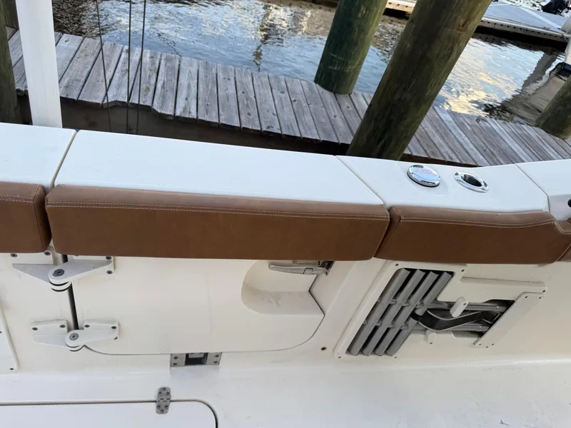 Slide: The Image of 2021 Scout 330 LXF boat interior with brown seating and dock view. - 75