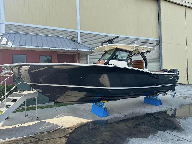 Slide: The Image of 2021 Scout 330 LXF boat on stands, displayed outdoors near a building. - 88
