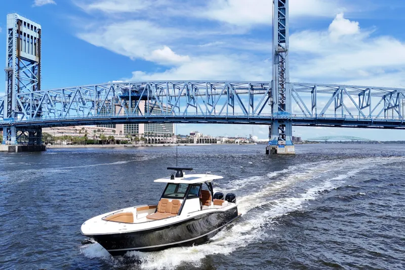 Slide: The Image of 2021 Scout 330 LXF boat cruising under a blue bridge on a sunny day. - 92