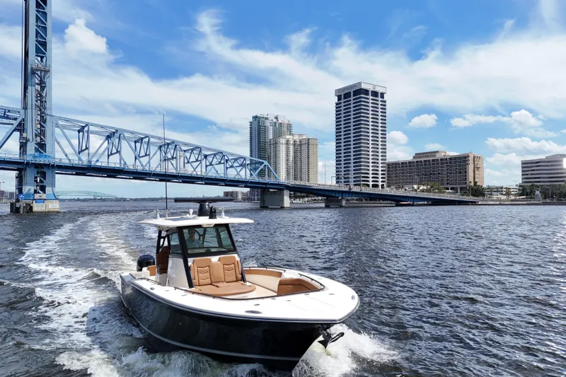 Slide: The Image of 2021 Scout 330 LXF boat cruising near a city bridge with skyscrapers in the background. - 93